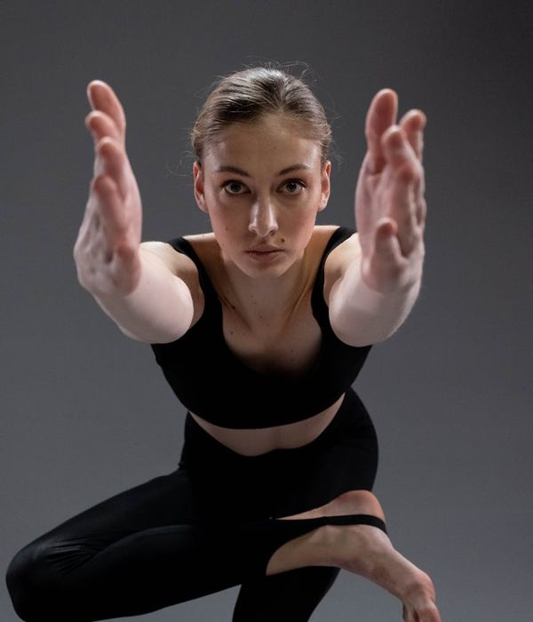 Young woman practicing stretching yoga pose in a dark room.